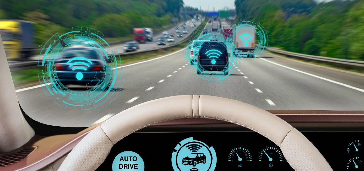 A digital rendering image view from inside a vehicle looking through the windshield at a highway with traffic, overlaid with a digital head-up display showing AUTO DRIVE ACTIVE status, network connection icons over other vehicles, and speedometer gauges