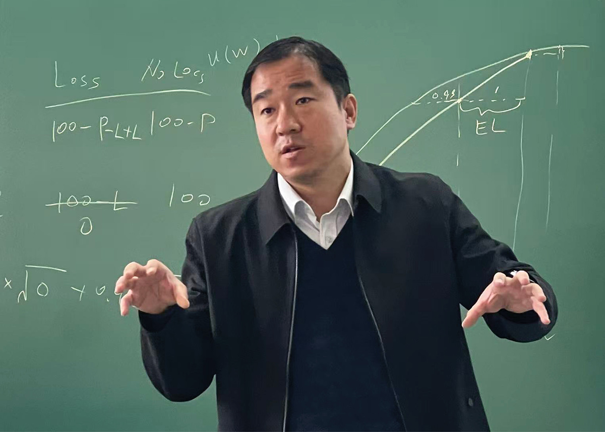Xiaoxuan (Sherwin) Li gesturing with both his hands lecturing in front of a green chalkboard containing mathematical notations related to economics