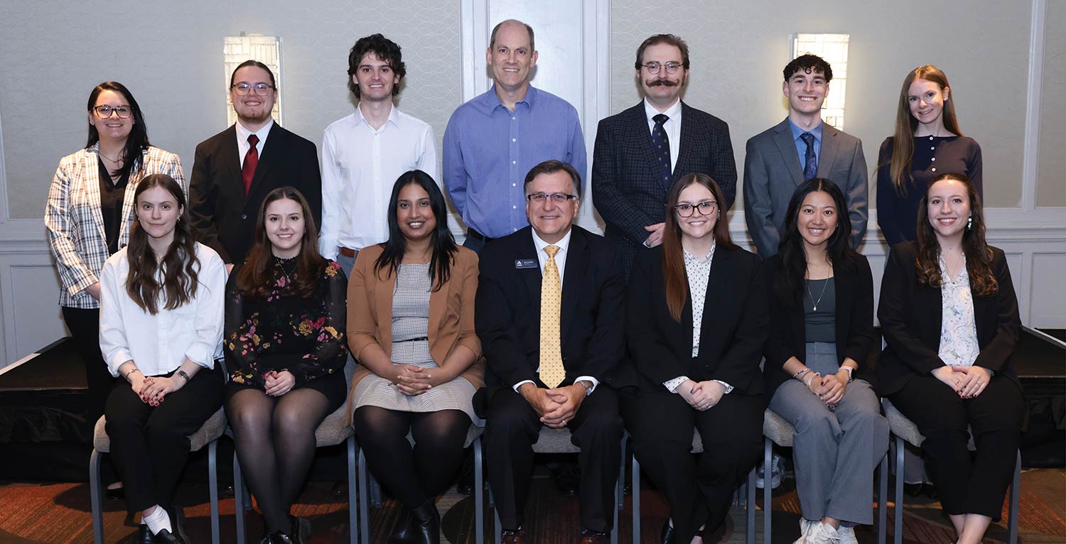 Group portrait of new CAS associates smiling alongside the CAS President.